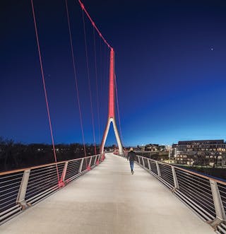 Unity Bridge glowing at night. The pedestrian bridge crosses Bristol Street  and connects South Coast Plaza with The…