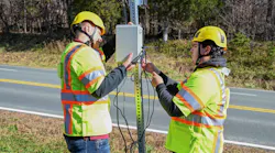Virginia Tech Transportation Institute researchers (from left) Will Vaughn and Daniel Burdisso install part of the VTTI Smart Work Zone on a road sign. Photo by Jean Paul Talledo Vilela for Virginia Tech.