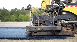 Industrial pavement truck laying fresh asphalt on construction site