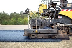 Industrial pavement truck laying fresh asphalt on construction site