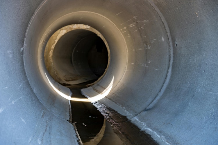 A drainage culvert with water trickling through it.