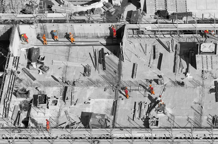 Construction workers laying out a new bridge, working in their various job functions.