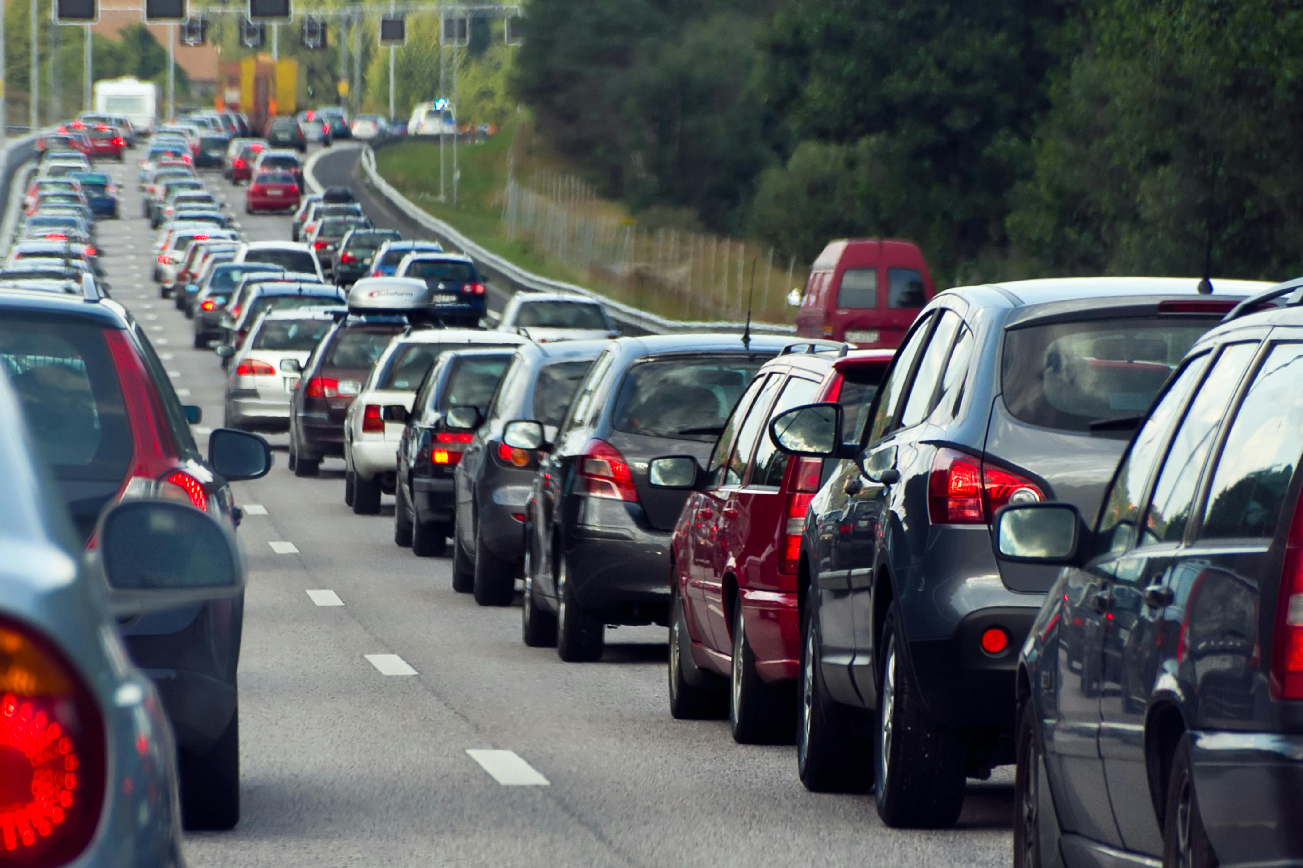 Vehicles lined up in a traffic jam during on a three-lane highway during rush hour.