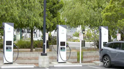 Three electric vehicle chargers and an electric vehicle being charged in a parking lot in California.
