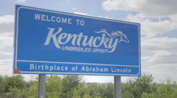 A Welcome to Kentucky sign located along the side of a highway.
