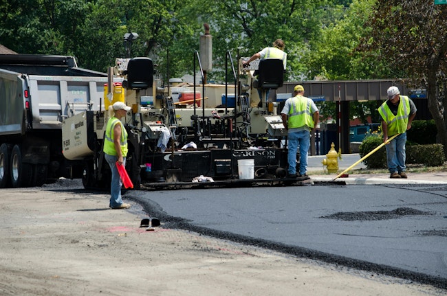 Workers completing repaving work on a roadway.