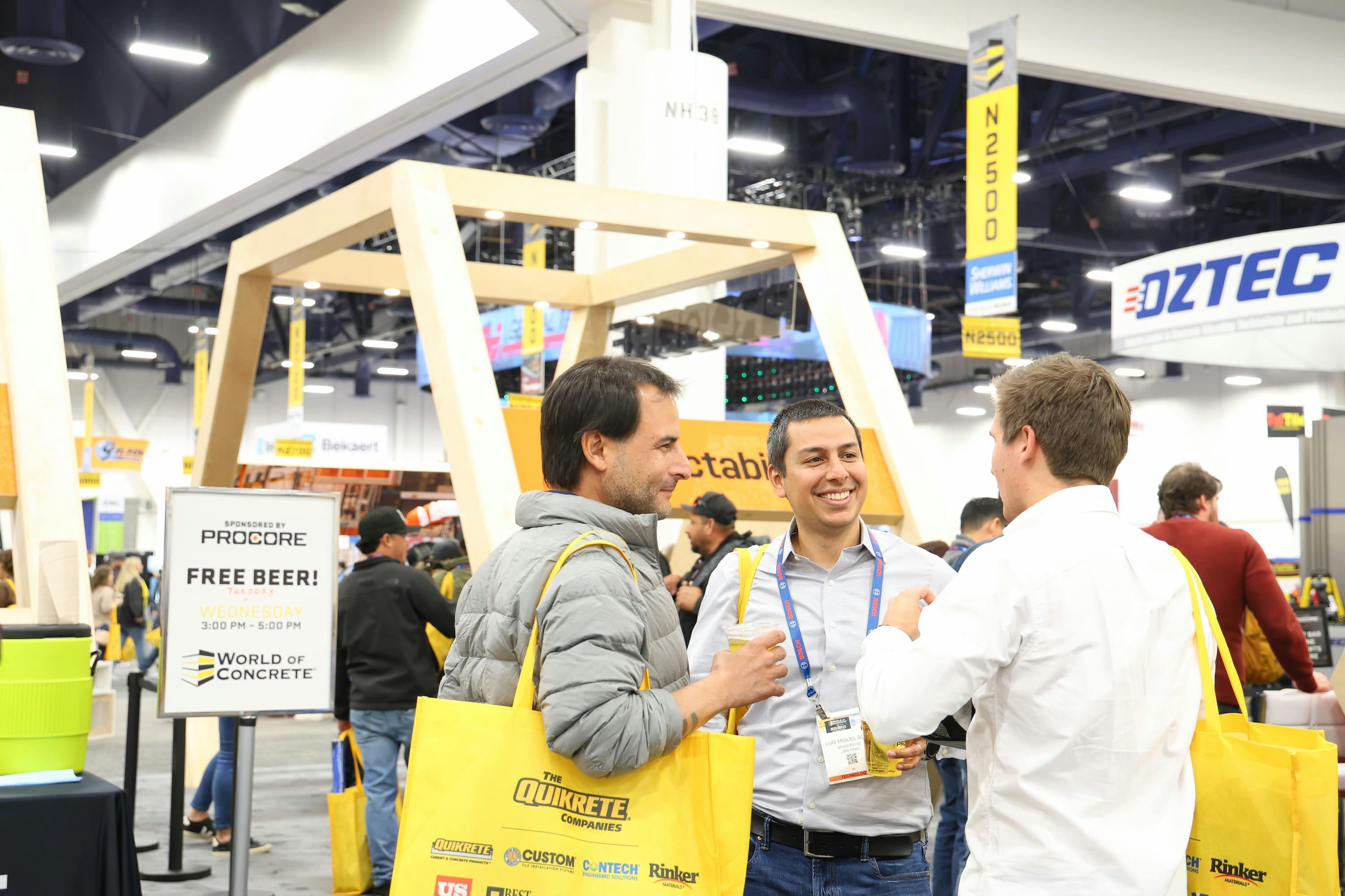 Three attendees of World of Concrete talking on the trade show floor.