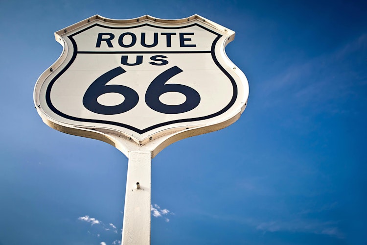 A historic Route 66 road sign flanked by blue skies.