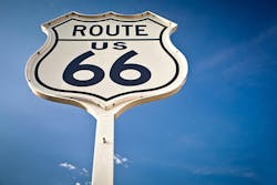 A historic Route 66 road sign flanked by blue skies. A historic Route 66 road sign flanked by blue skies.