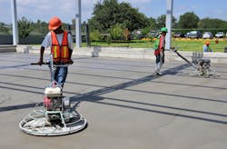Two workers finishing a concrete floor with a smoothing machine. Two workers finishing a concrete floor with a smoothing machine.