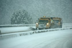 A snow plow clearing a roadway blanketed with heavy snow. A snow plow clearing a roadway blanketed with heavy snow.