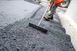 A person laying asphalt on a roadway. A person laying asphalt on a roadway.