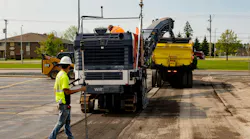 Trucks milling asphalt in a parking lot.