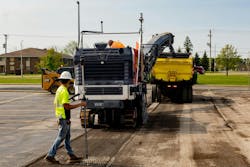 Trucks milling asphalt in a parking lot. Trucks milling asphalt in a parking lot.