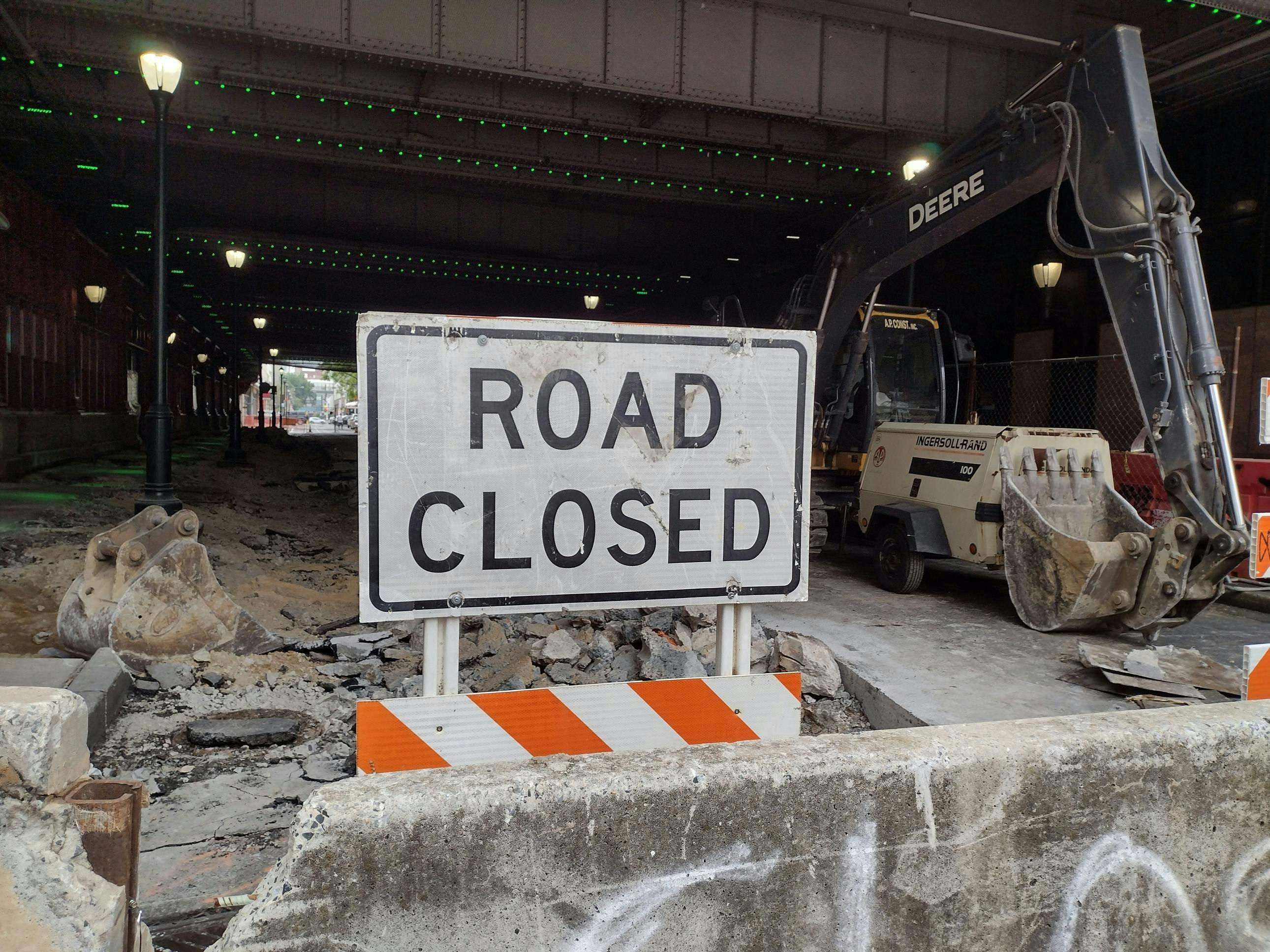 A road closed sign outside of a construction site in an urban area.