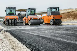 Road pavers driving along a roadway during a construction project. Road pavers driving along a roadway during a construction project.