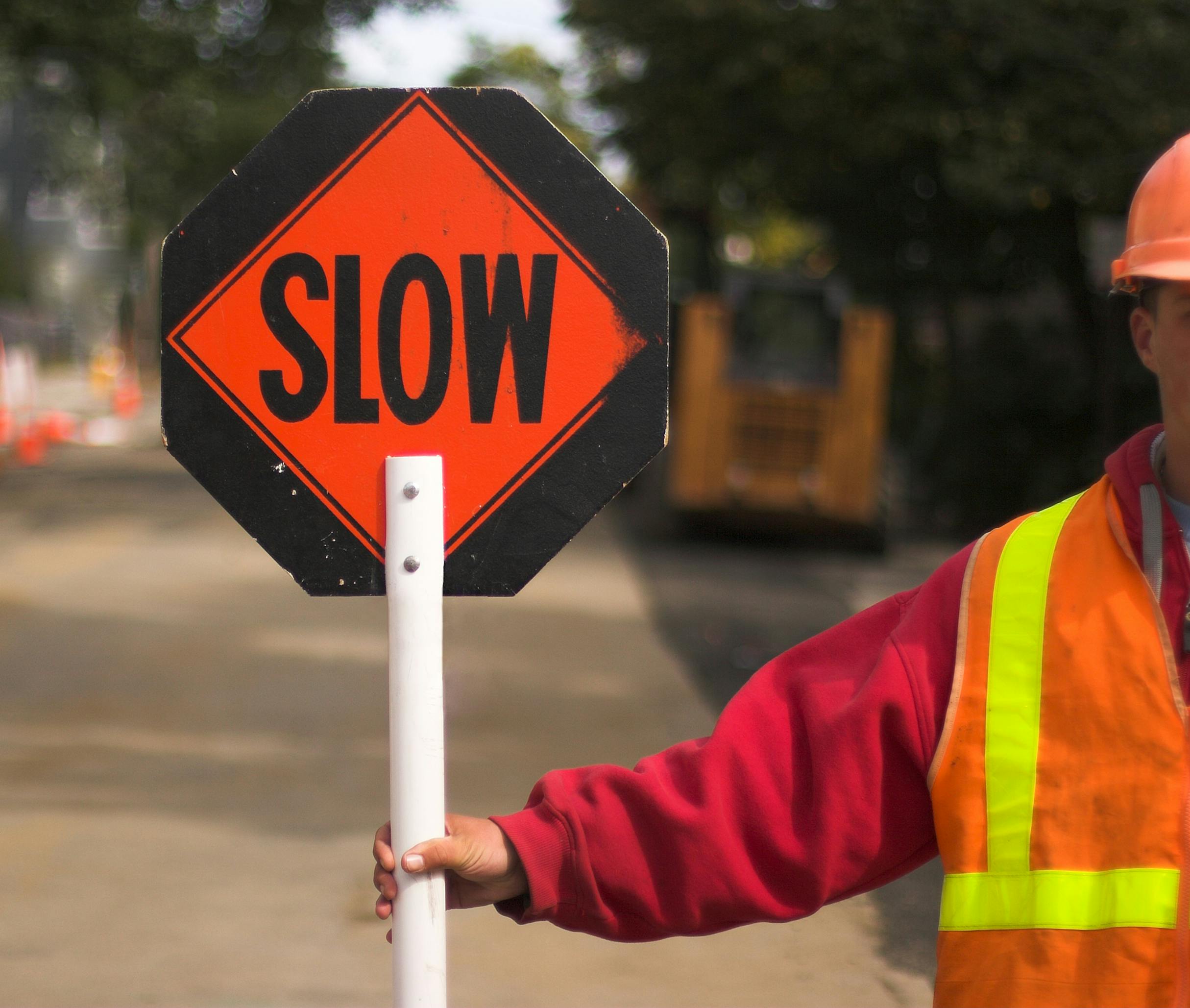 A flagger holding a slow sign in a work zone.