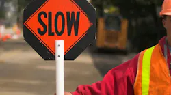 A flagger holding a slow sign in a work zone.