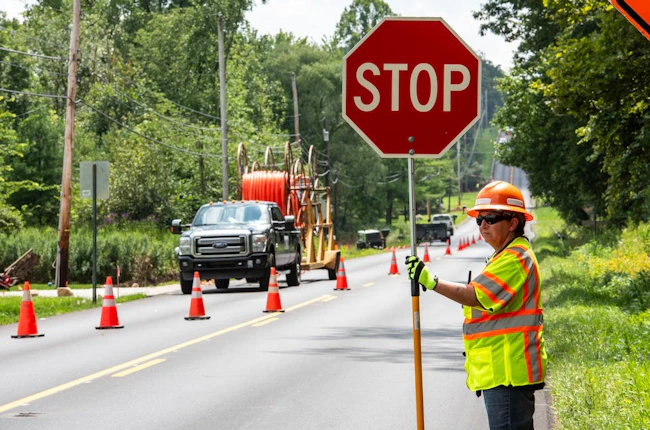 A flagger holding a stop sign for traffic passing a work zone.