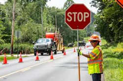 A flagger holding a stop sign for traffic passing a work zone. A flagger holding a stop sign for traffic passing a work zone.