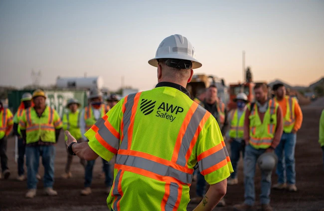 A road worker wearing his safety vest with the back reading 'AWP Safety.'