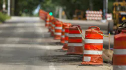 Safety barrels lining a work zone along a roadway.