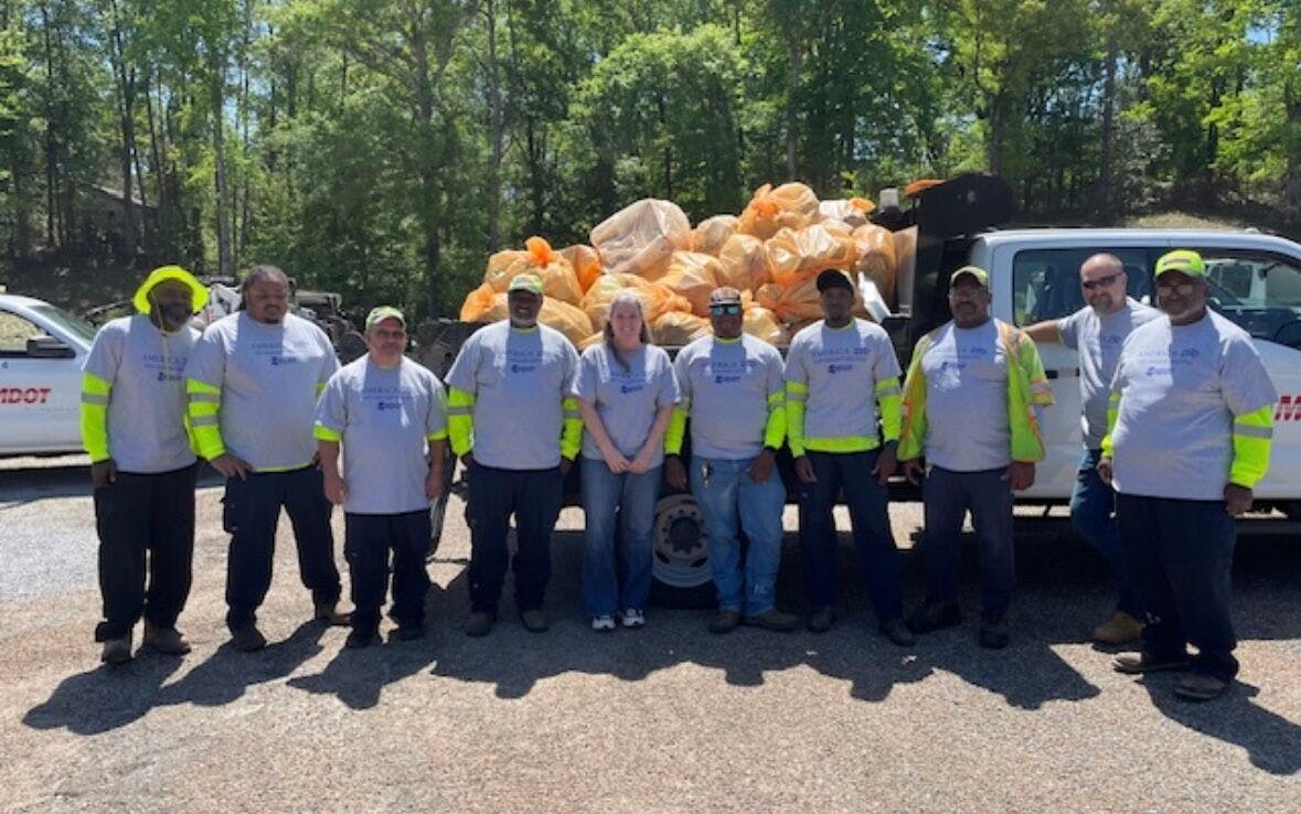 An MDOT crew in front of a truck holding the bags of litter they cleaned up.