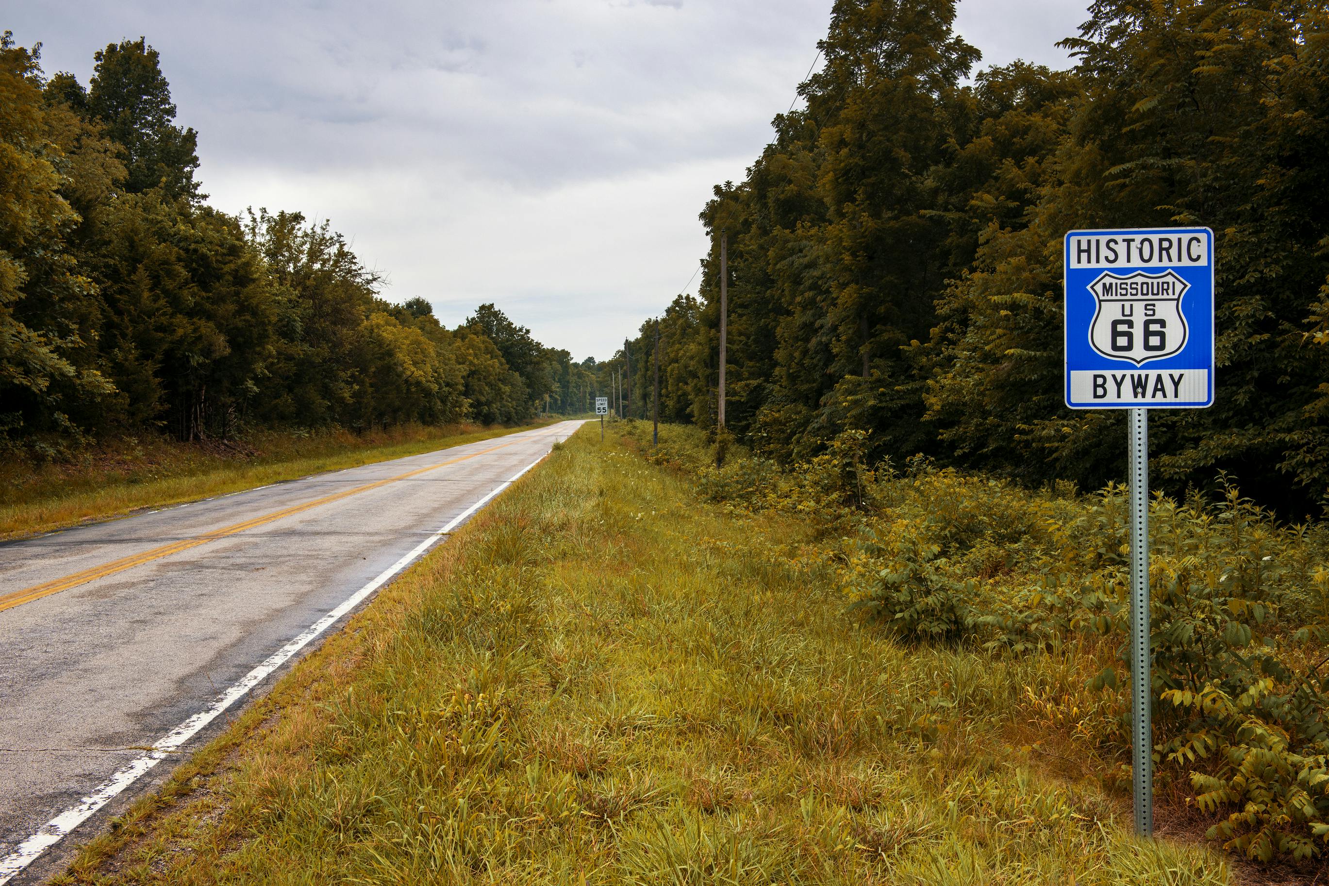 A stretch of the original route 66 with a road sign in a rural area of Missouri