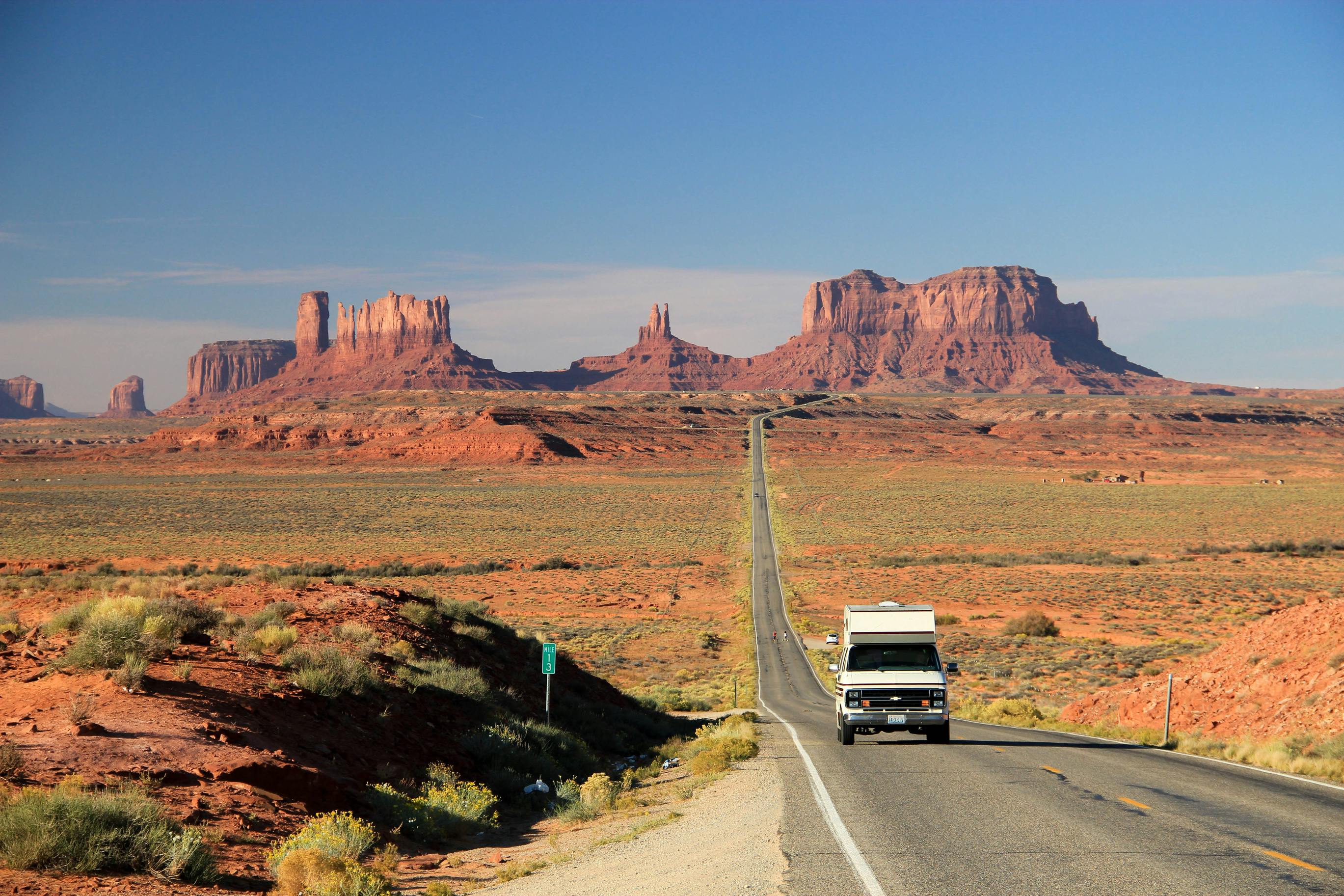 An RV camper van travels through Monument Valley along the Arizona-Utah border, reflecting the cross-country travel theme featured in The Great American Road Trip.