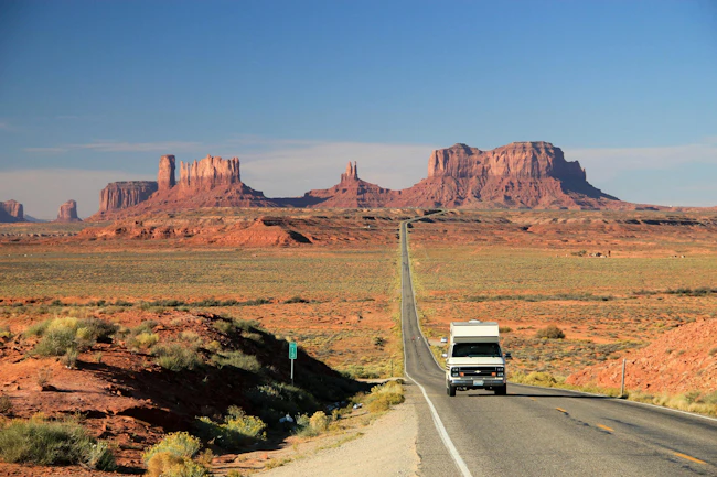 An RV camper van travels through Monument Valley along the Arizona-Utah border, reflecting the cross-country travel theme featured in The Great American Road Trip.