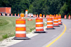 A highway work zone with a barrier of barrels.