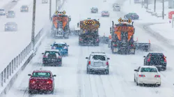 Traffic behind a fleet of plows on a snowy highway.