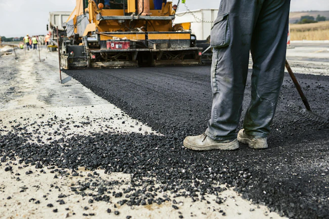 A worker operates an asphalt paver during a road construction project