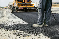 A worker operates an asphalt paver during a road construction project