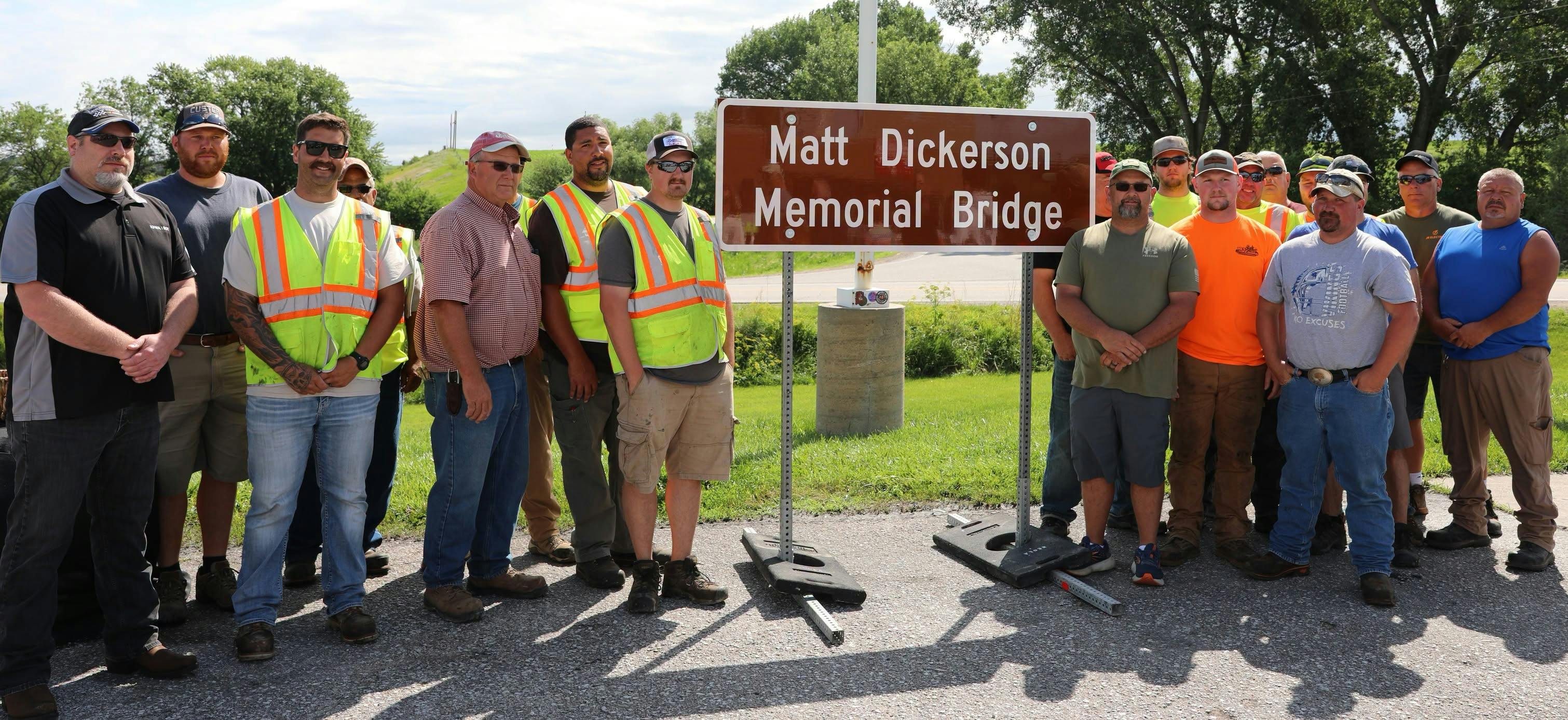 Iowa DOT District 4 staff and Matt Dickerson&rsquo;s coworkers gather around the newly unveiled Matt Dickerson Memorial Bridge sign during the dedication ceremony in Neola on June 11.