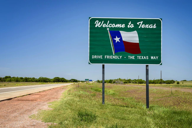 A Welcome to Texas sign along the roadway.
