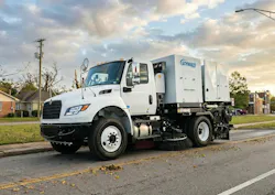 A street sweeper being used along a roadway.