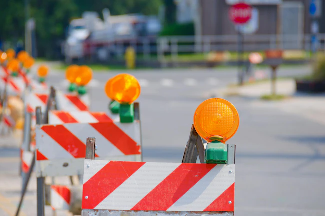 Stock photo of a row of road traffic barricades with yellow warning lights guiding vehicles through a work zone.