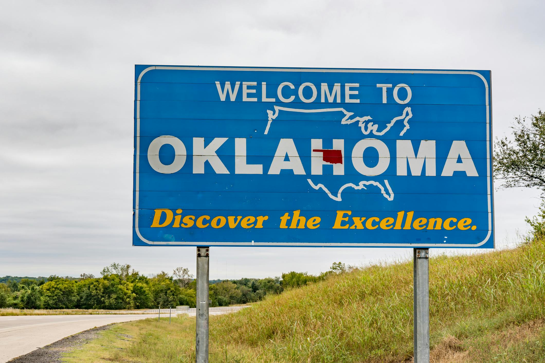 A welcome to Oklahoma sign situated next to the highway.
