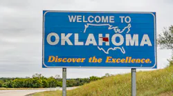 A welcome to Oklahoma sign situated next to the highway.