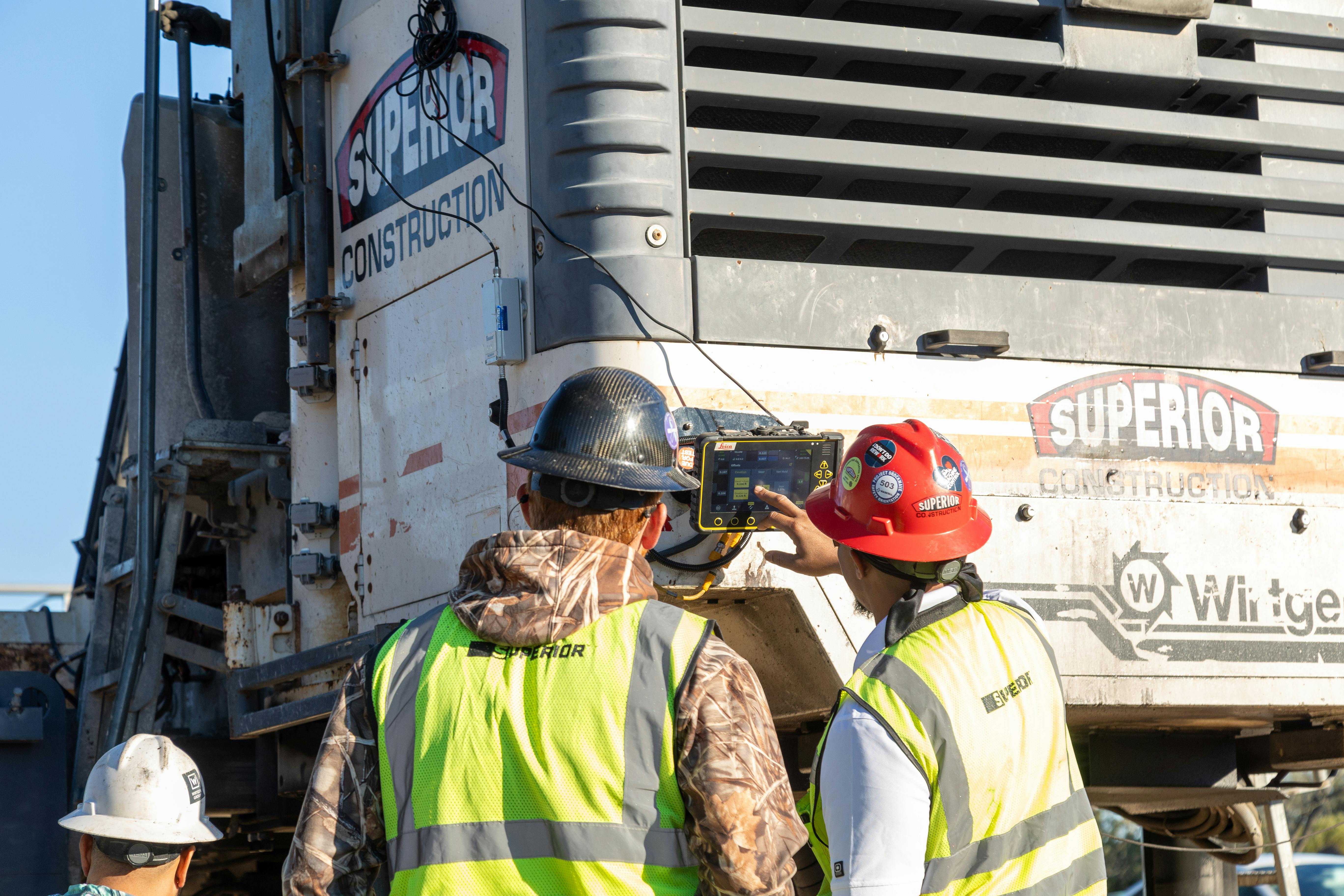 Two crew members using a tech system mounted on the back of a truck.