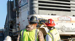 Two crew members using a tech system mounted on the back of a truck.