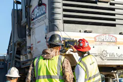 Two crew members using a tech system mounted on the back of a truck.