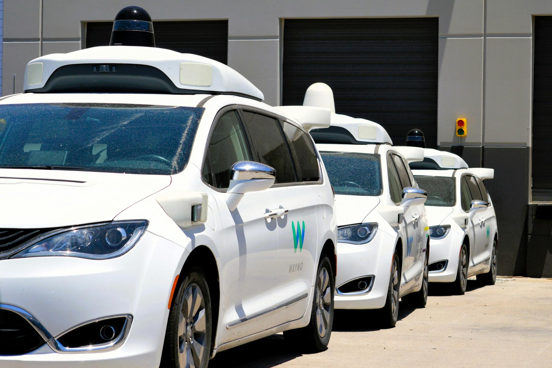 Waymo vans lined up at a parking facility.