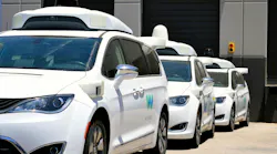 Waymo vans lined up at a parking facility.
