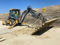 A crew member using equipment to construct a cattle guard.